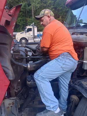 ATL Mobile Mechanics — Joseph climbing onto a red commercial semi's front end to inspect the engine compartment